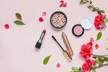 Obraz na płótnie Canvas Various cosmetic products for make-up with red flowers on a pink background with copy space. Makeup Accessories Top view Flat Lay. Powder Rouge Eyeshadow Pomade Brushes Mascara