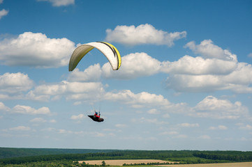 Paragliding over the green field in summer sunny day. One paraglider fly over green field near Dnister river in Ukraine.