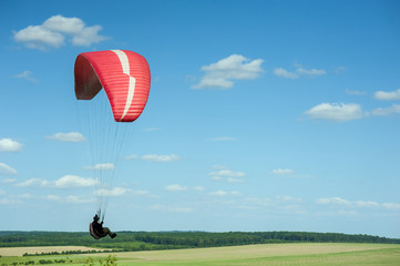 Paragliding over the green field in summer sunny day. One paraglider fly over green field near Dnister river in Ukraine.