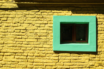 Yellow brick wall background with green window