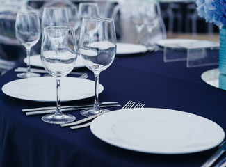 Tableware and silverware with glasses and flower decoration arranged on tablecloth for restaurant banquet