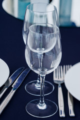 Wine glasses with tableware arranged on tablecloth for reception or banquet
