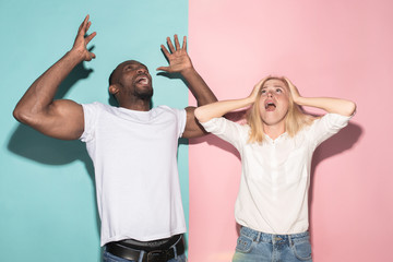 We won. Winning success happy afro man and woman celebrating being a winner. Dynamic image of caucasian female and male model on pink studio.