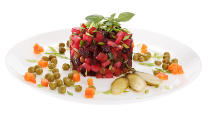 Vinaigrette salad is served on a  plate, decorated with fresh Basil, pickles, boiled carrots and green peа. Isolated on white background.
