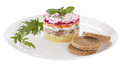 Salad herring under a fur coat, decorated with fresh Basil. Isolated on white background.