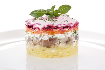 Salad herring under a fur coat, decorated with fresh Basil. Isolated on white background.