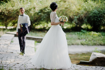 Fototapeta na wymiar Young newlyweds walking in the park on their sunny wedding day.