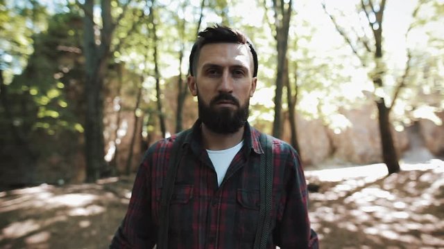 Portrait of handsome bearded man walking in the forest. A lumberjack looking into the camera