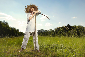 Village natural country man on summer meadow mowing grass with classic scythe