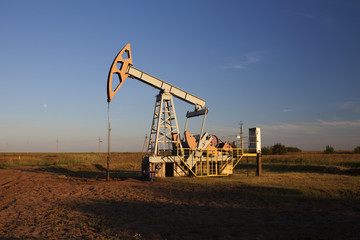 The oil pump, industrial equipment. Oil rocking at sunset in Russia, Republic of Bashkortostan