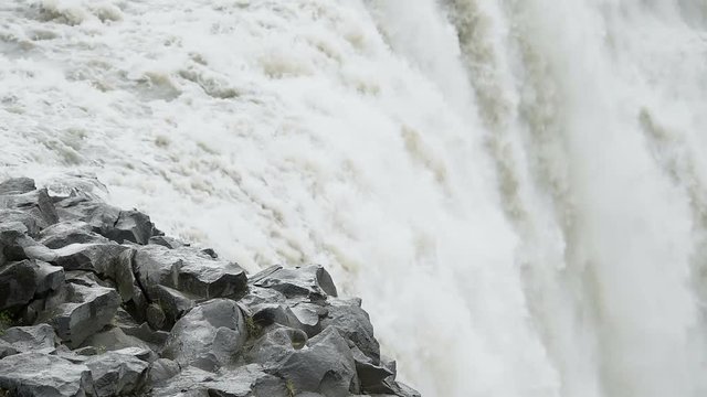 Iceland Dettifoss waterfall, largest greatest volume in Europe closeup, gray grey water, rocky cliff and water flowing with sound