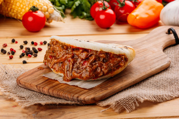 Arepa with seasoned mashed meat and some ingredients of its preparation around