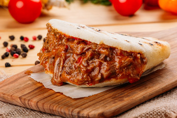 Arepa with seasoned mashed meat and some ingredients of its preparation around