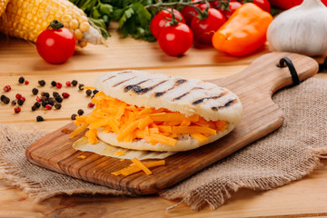 Arepa with cheddar cheese on a cutting board