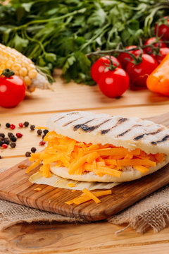 Arepa with cheddar cheese on a cutting board