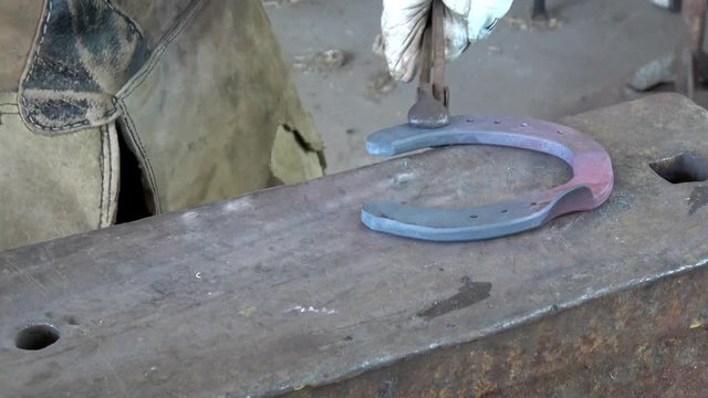 Schmiedearbeit, ein Hufeisen wird auf einem Amboss bearbeitet (geschlagen)