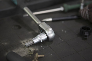 Car workshop tools left lying around on the floor. Workshop floor greasy and dirty.