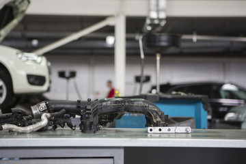 Car service In the foreground engine parts on the table, on a blurry background cars on the ski lifts