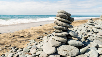 Maspalomas, Canarias islands/ Spain-July 22, 2018: Gray stones on sand from Sahara desert and distance view of blue Atlantic ocean and beach on Canarias island, Gran Canaria.