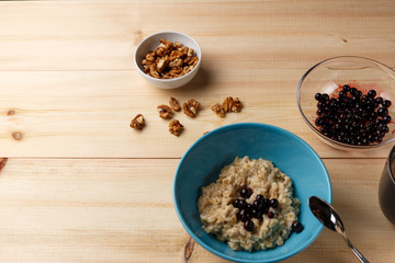 Porridge in a bowl with the berries, walnuts and cocoa on bright wooden table. Healthy breakfast image. Copy space