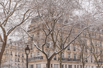 Paris under the snow, typical building facades in winter in a beautiful french neighborhood 
