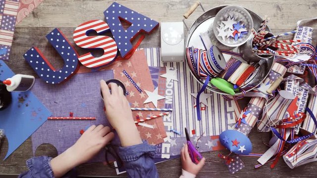 Step by step. Mother and daughter making neckles from paper straws and stars for July 4th celebration