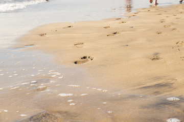 Maspalomas, Canarias islands/ Spain-July 22, 2018: Couple of man and woman walking on Canarias sand from Sahara desert, view of wet foot traces. Blue Atlantic ocean and beach on Gran Canaria.