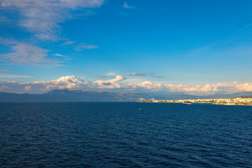 View from the ferry ship on the Rion-Antirion bridge and port of Patra city at sunset in the Ionian Sea, Greece