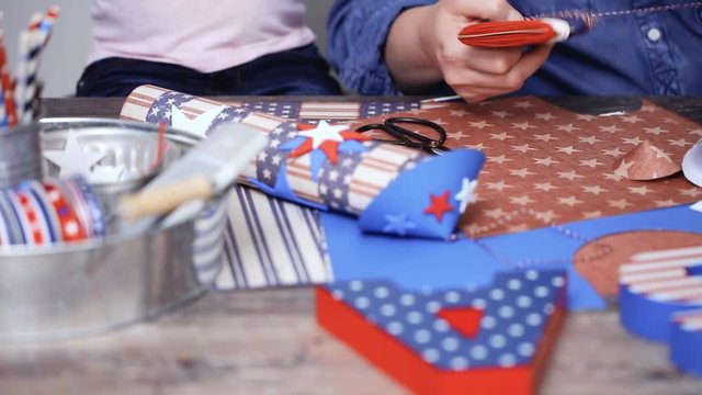 Step by step. Mother and daughter making paper firecrackers for July 4th celebration