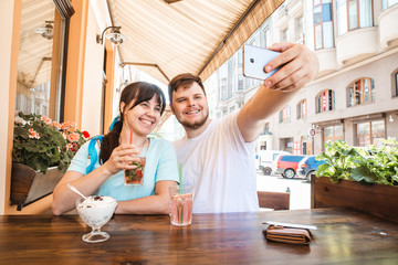 couple sitting in cafe in summer day taking selfie. cool drinks