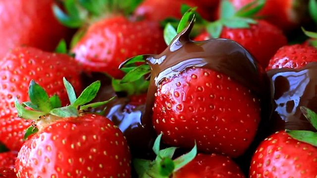 Chocolate flows down on ripe strawberry