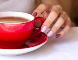 Woman's hand holding a red cup of coffee.