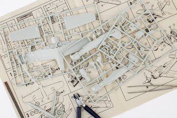 kit for assembling gray plastic airplane model on white bsckground