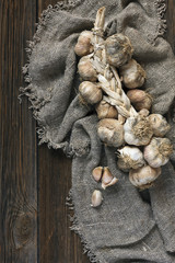 A bunch of garlic on canvas fabric in  rustic style. Top view, close-up on  wooden vintage background.