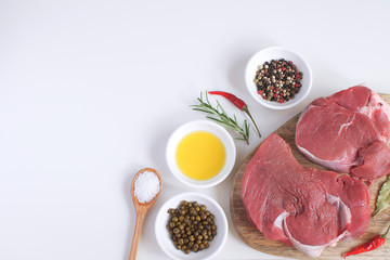 Fresh raw meat beef steak olive oil Spices Hot Salt Wooden spoon Pepper Rosemary Cooking concept Cooking concept White background Top view Copy space Flat lay