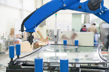 Industrial automated robot arm holding car glass in factory