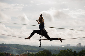 Young woman trying to sit on twine on the slackline rope