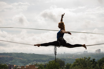 Young woman sitting on twine on the slackline rope