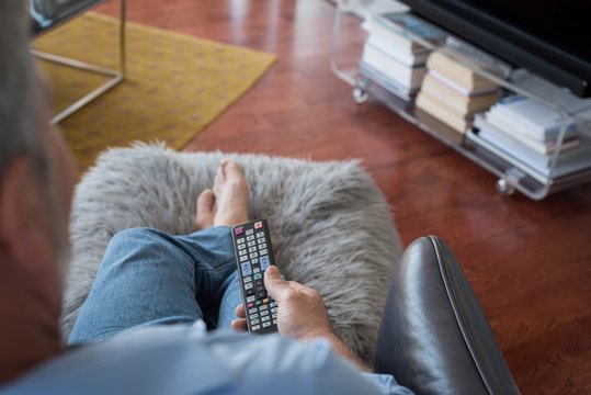Man changing channels while watching television in living room