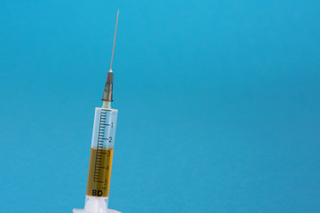 Syringe with injection on a blue background. Concept of medicine and public health.