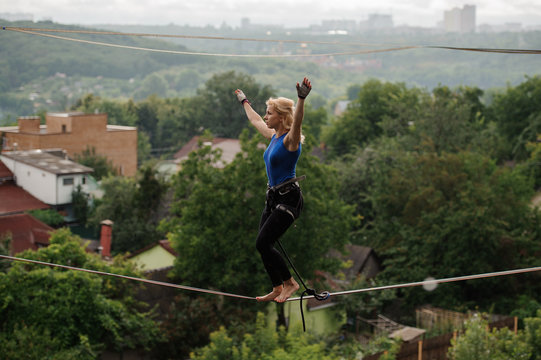 Woman standing on the slackline rope on the bending knees