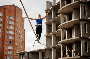 Young woman standing with arms raised on the slackline rope