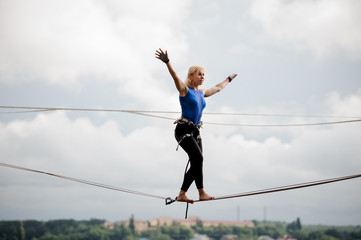 Young woman standing on the slackline rope and looking into the distance