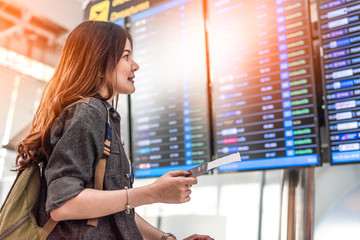 Beauty Asian female tourist looking at flight schedules for checking take off time. People and lifestyles concept. Travel and Happy life of single woman theme. Back view portrait.