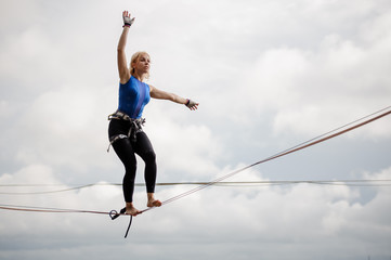 Young woman balancing on the slackline rope and looking into the distance