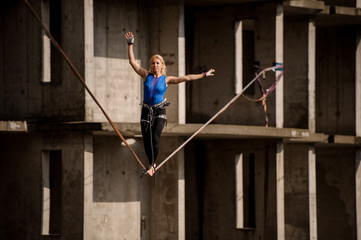 Female equilibrist balancing with one arm raised and other to the right on the slackline