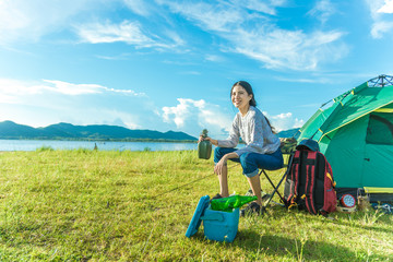 Happy woman drinking alcohol while camping at meadow. People and Lifestyles concept. Travel and adventure theme. Female tourist portrait