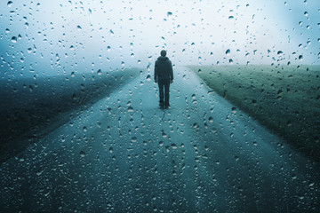 Fototapeta Lonely man stands on misty road with artistic raindrops background. obraz