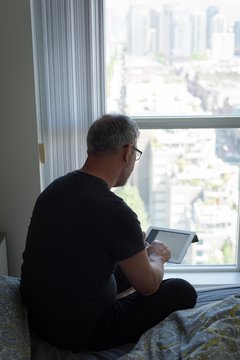 Man using digital tablet in bedroom at home
