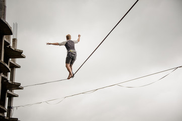 Young active man walking on the slackline rope